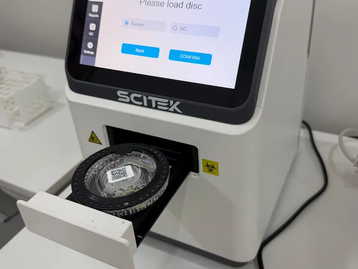 SCITEK analyser with an open tray and test disc.
