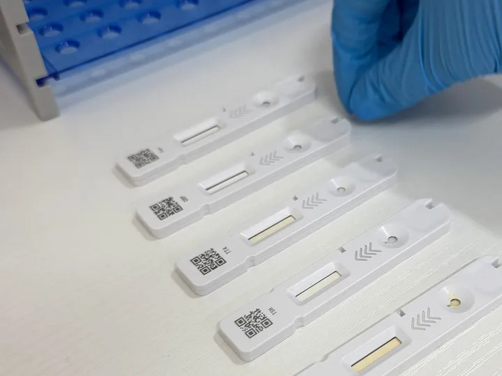 Close-up of test cassettes and a blue-gloved hand.