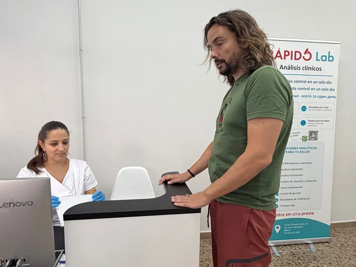 Atenció a una persona al taulell de recepció de Rápido Lab.