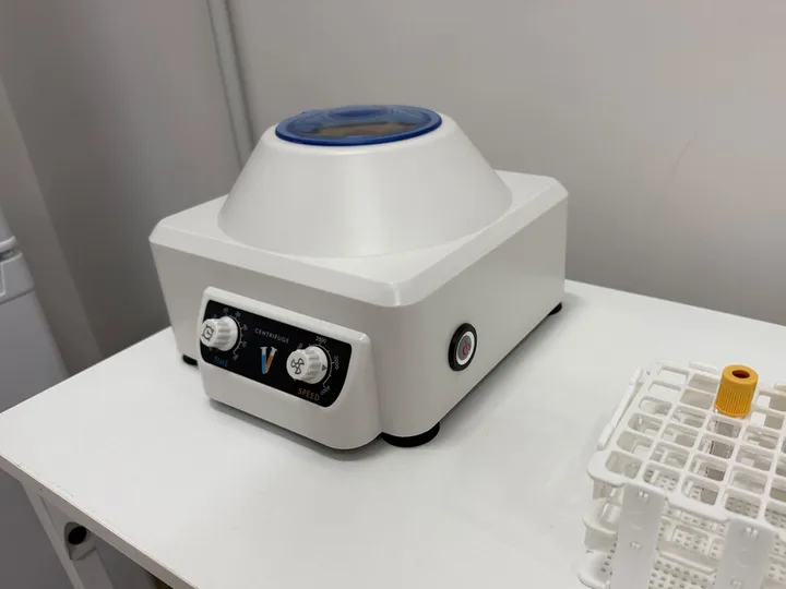 Centrifuge and tube rack on a laboratory table.